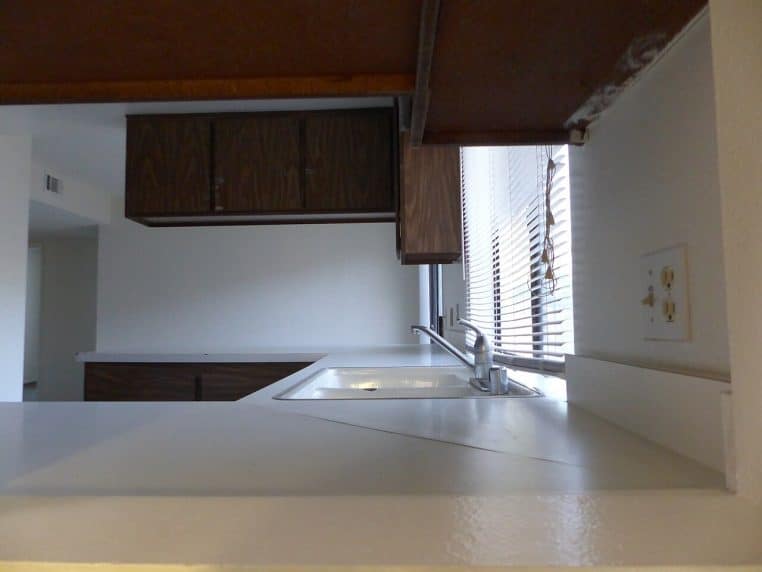 Cuisine californienne 1980 avec façades brillantes, plan de travail clair et éclairage doux, style rétro-moderne.