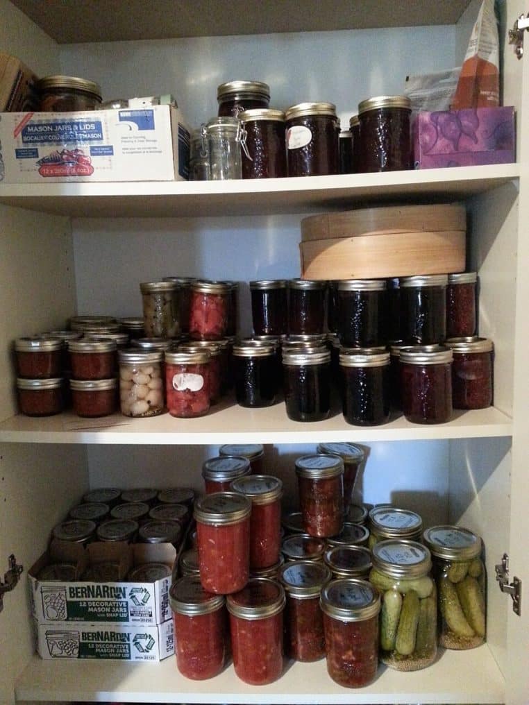 Rangée de bocaux maison de sauces, ketchup et concentré de tomate alignés sur une table de cuisine après stérilisation.