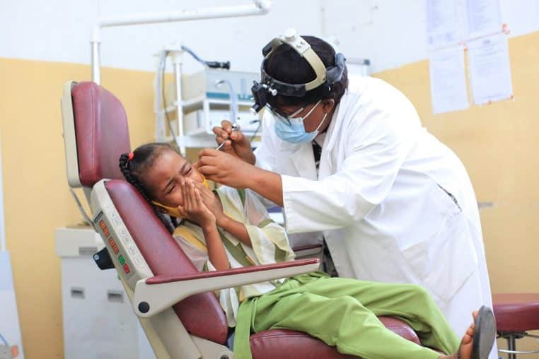 Médecin ORL examinant un enfant dans un service hospitalier, avec matériel d’otoscopie et personnel soignant.