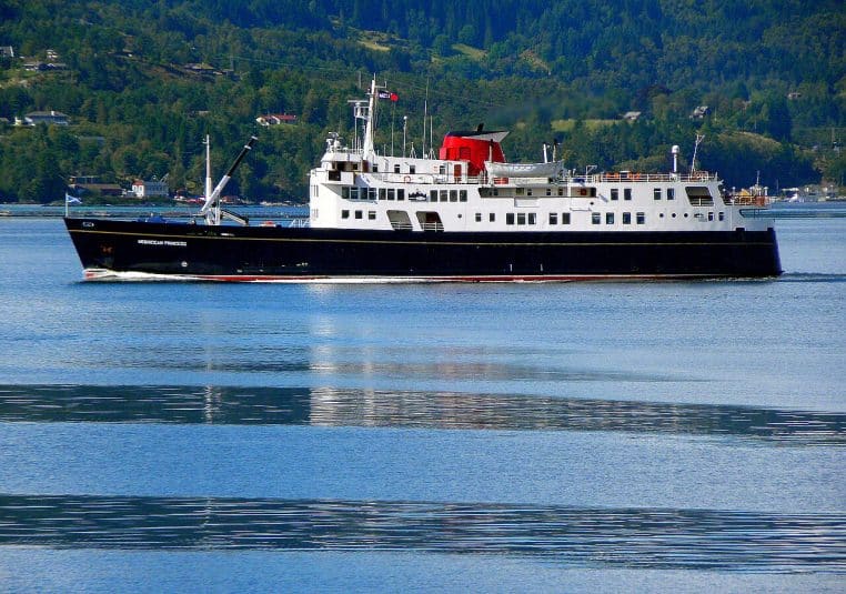 Le MV Hebridean Princess glisse dans l’Osterfjord en Norvège, paquebot bien centré, reliefs forestiers et eau immobile au premier plan.