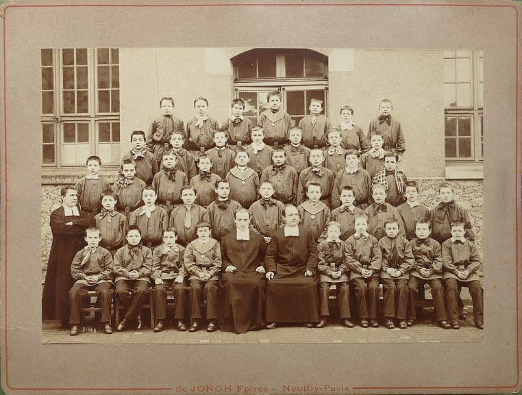 Groupe d’élèves d’une école jésuite parisienne vers 1890, posant en uniforme, décor urbain en arrière-plan.