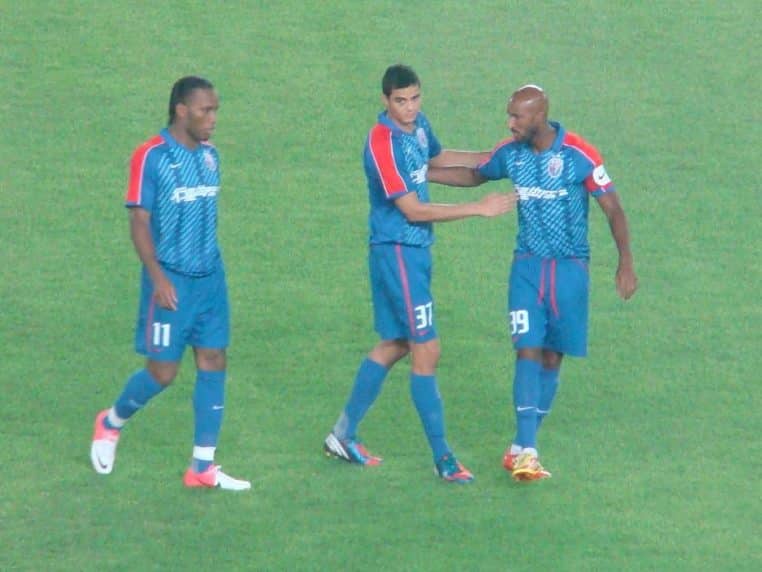 Didier Drogba et Nicolas Anelka en maillot du Shanghai Shenhua, côte à côte sur la pelouse lors d’un match en Chine.