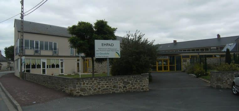 Bâtiment d’un Ehpad en Normandie, façade horizontale et parkings attenants sous ciel dégagé.