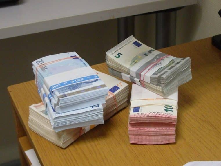 Importante pile de billets en euros empilés sur table, vue en format paysage haute définition.