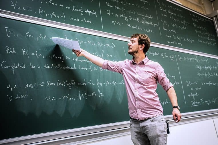 Étudiants concentrés lors d’un cours à l’École polytechnique, tableau numérique et poste de professeur au premier plan.