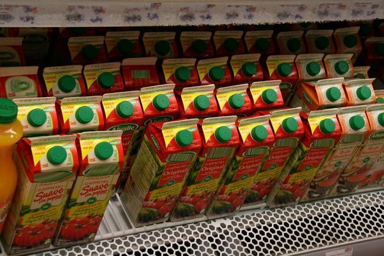 Briques de gazpacho alignées au frais dans un supermarché, bouchons verts visibles, étagère réfrigérée