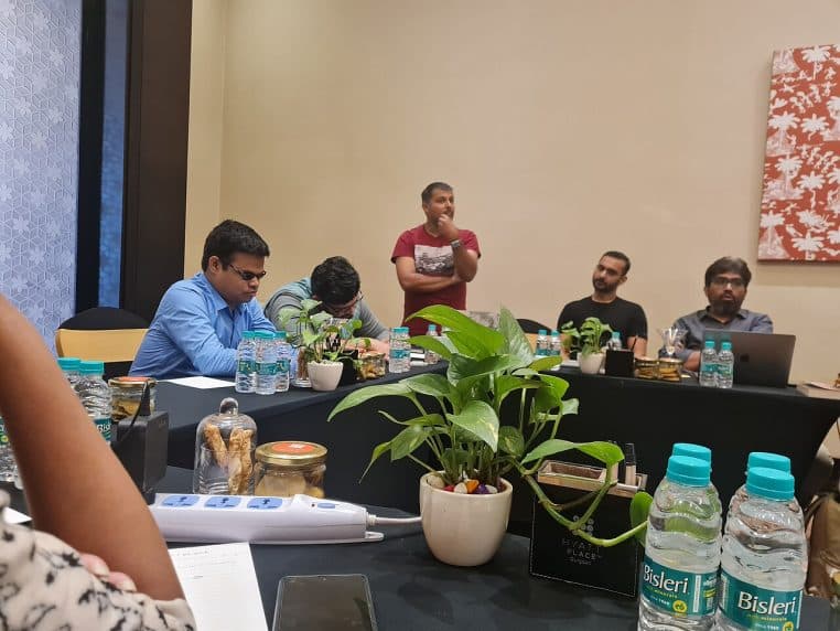 Réunion stratégique captée en plan large, ambiance studieuse