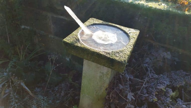 Abreuvoir à oiseaux gelé formant un pic de glace, vue de trois-quarts dans un jardin givré.