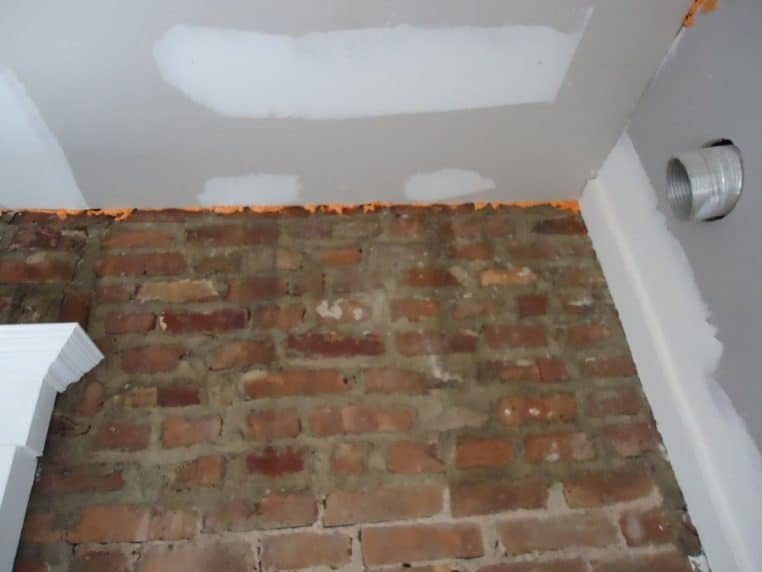 Plafond et mur montrant une fissure comblée pendant une rénovation, zone traitée encore visible.