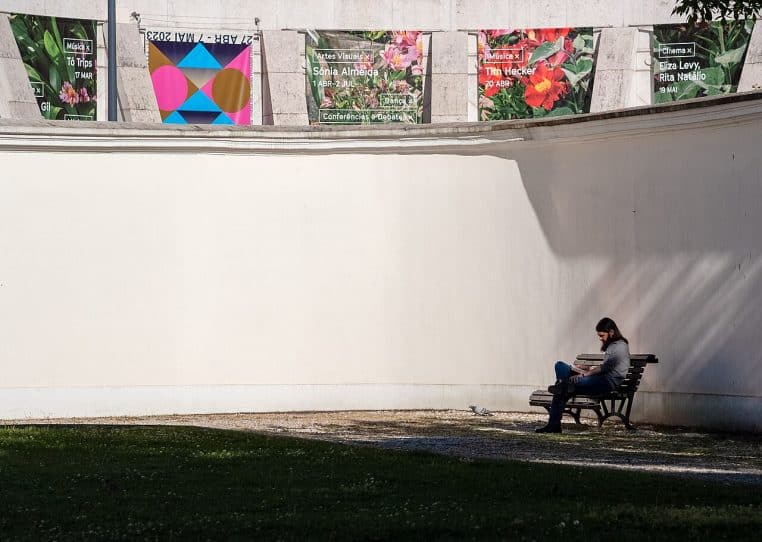 Homme assis seul sur un banc du Palácio das Galveias à Lisbonne, plongé dans un livre par une après-midi ensoleillée