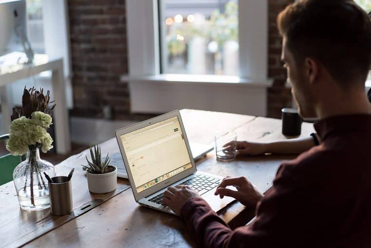 Homme concentré devant son ordinateur au bureau, posture ouverte, prêt à écouter et à reformuler.