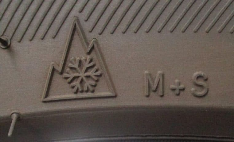 Gros plan sur le flanc d’un pneu montrant le marquage hiver avec symbole alpin et flocon de neige réglementaire.