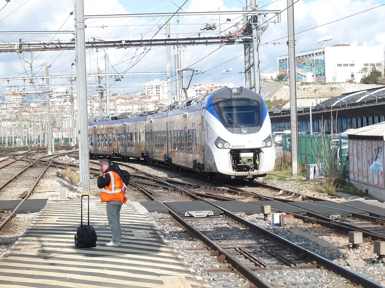 Rame B 84500 à quai à Marseille-Saint-Charles, vue de trois-quarts, caténaires et voyageurs visibles.