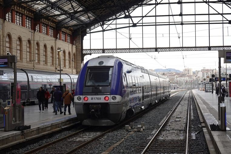 Vue de quais à Marseille-Saint-Charles avec une rame TER en service régional, prise en 2025, ciel dégagé et voyageurs sur le quai.