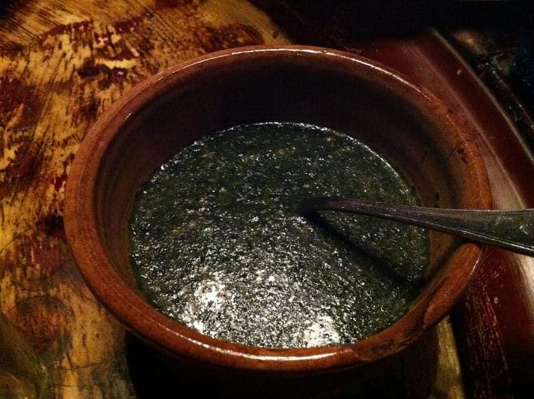 Bol en terre cuite rempli de molokheya bien verte et onctueuse, servi chaud avec une cuillère dans un restaurant égyptien.