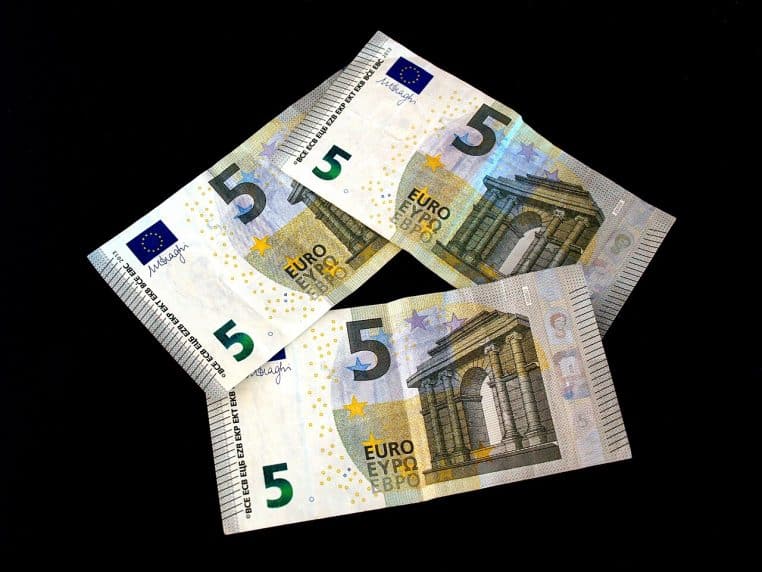 Trois billets de 5 euros de la nouvelle série disposés en éventail sur un fond noir montrant clairement les détails de sécurité et la valeur