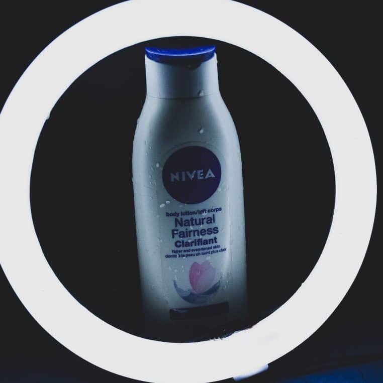 Flacon de lait pour le corps Nivea éclairé par un anneau lumineux blanc sur fond noir, rappelant l’univers moderne des soins hydratants.