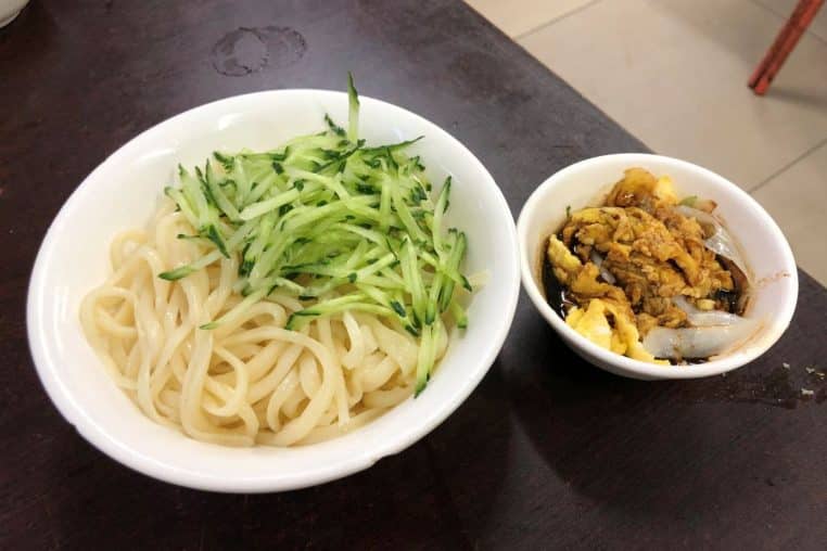 Nouilles garnies d’œufs brouillés et de sauce soja dans une assiette familiale, parfaites pour illustrer un dîner simple, gourmand et économique.