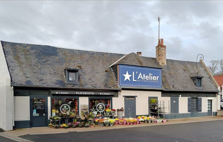 Boutique « L’Atelier » à Nouvion, façade avec enseigne et présentoirs de plantes, vue frontale nette au format horizontal.