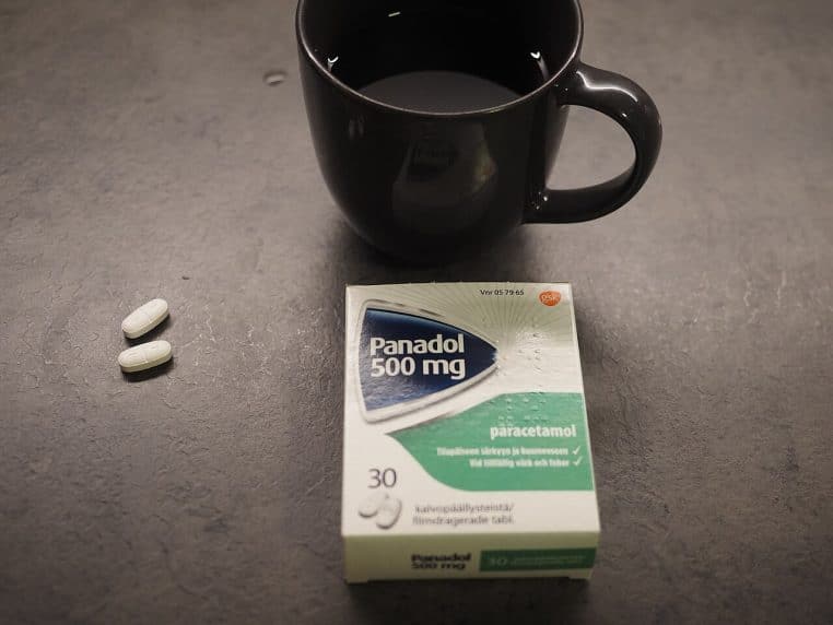 Boîte de médicament Panadol 500 mg posée sur une table, deux comprimés blancs et une tasse d’eau à côté, rappelant l’usage courant des antalgiques en France.