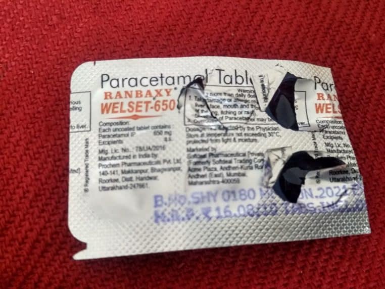 Plaquette de comprimés de paracétamol 650 mg partiellement utilisée, photographiée en gros plan sur un fond rouge, mettant en avant le conditionnement des médicaments.