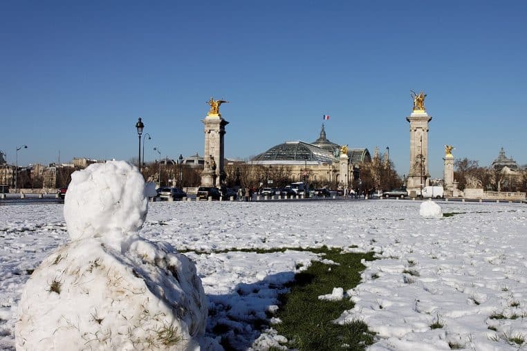 Vue large de l’esplanade des Invalides à Paris couverte de neige, perspective dégagée et arbres alignés par temps glacial.