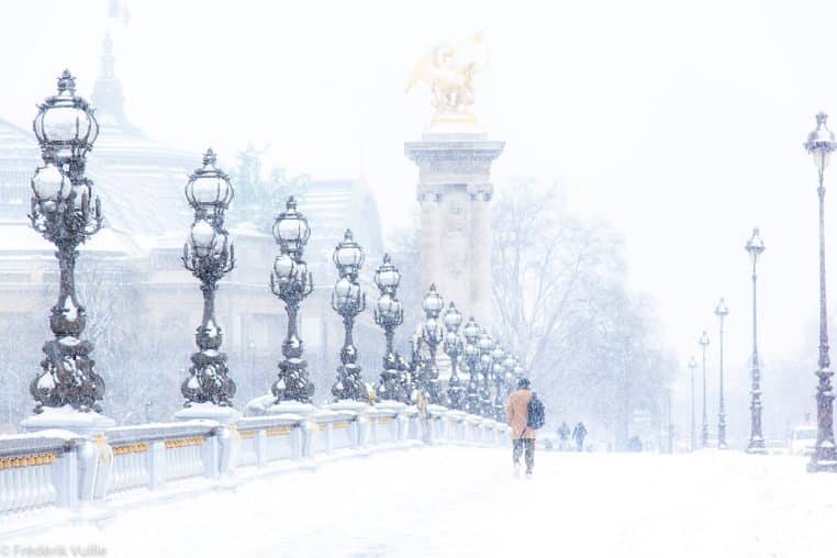 Le pont Alexandre III à Paris recouvert de neige, lampadaires alignés et piétons emmitouflés avançant dans la tourmente.