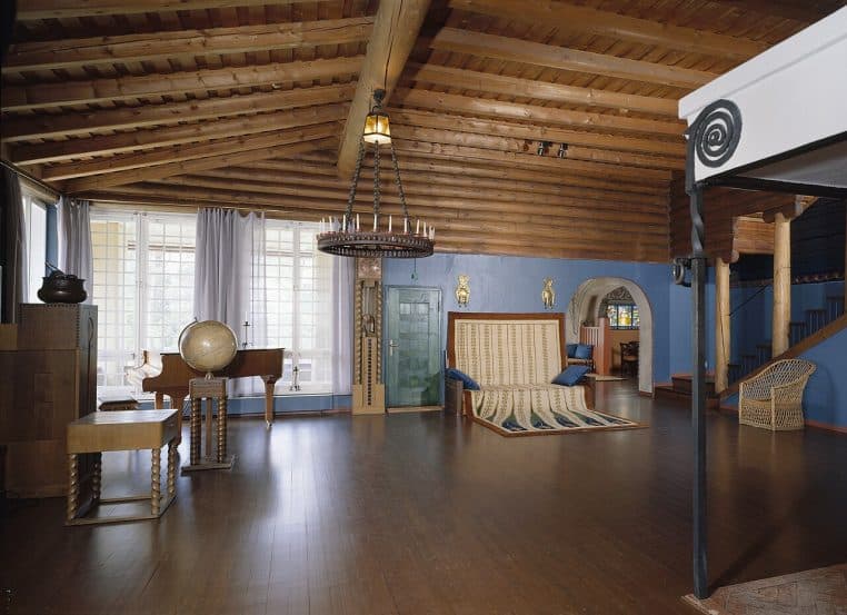 Salon finlandais boisé décoré avec sobriété, grandes fenêtres, mobilier simple et chaleureux, ambiance cosy illustrant un intérieur nordique apaisant.