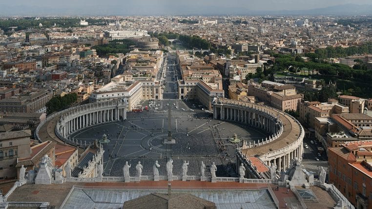 Panorama large de la place Saint-Pierre vue d’en haut, colonnades ovales et foule sur l’esplanade au Vatican.