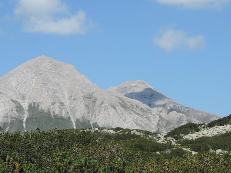 Sommet minéral du massif de Pirin baigné de lumière, dominant un tapis de végétation rase sous un ciel bleu au cœur des montagnes bulgares