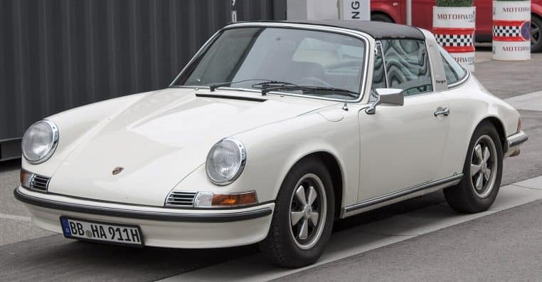 Porsche 911 Targa blanche garée en extérieur, capote ouverte, illustrant les lignes intemporelles des premières générations de 911.
