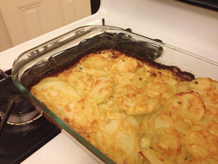 Gratin de pommes de terre maison dans un plat ovale posé sur la cuisinière, surface dorée et bords crémeux bien visibles après la cuisson
