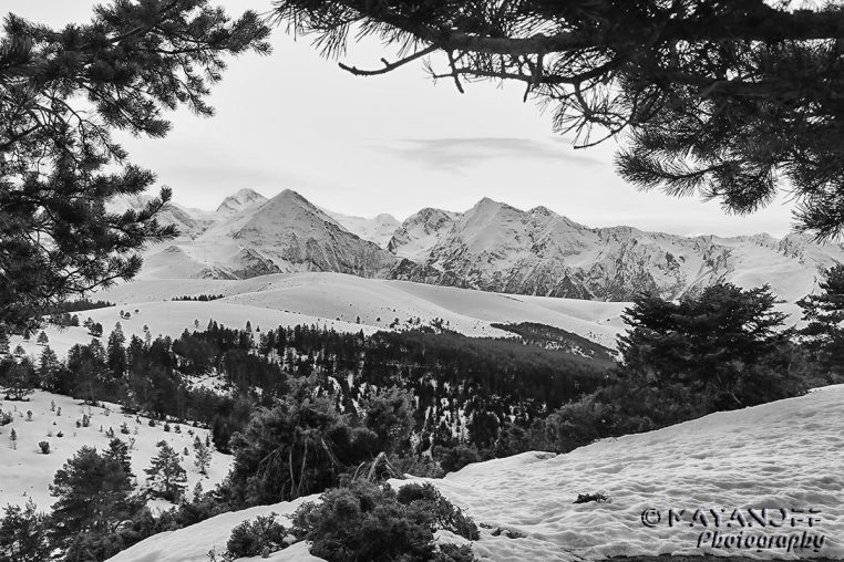 Crêtes pyrénéennes couvertes de neige en hiver, relief découpé et ciel nuageux au-dessus d’un paysage de haute montagne