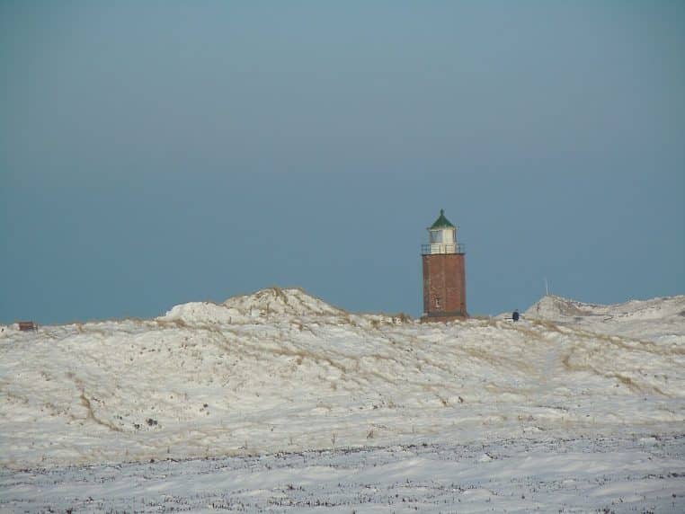 Phare du Rotes Kliff à Sylt au milieu des dunes enneigées sous un ciel pâle de décembre