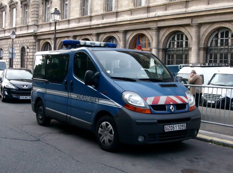Fourgon bleu de la gendarmerie nationale garé en ville devant un bâtiment officiel, prêt pour une intervention des militaires