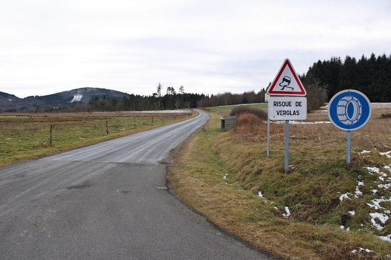 Panneaux routiers annonçant risque de verglas et chaînes à neige obligatoires le long d’une route départementale en hiver.