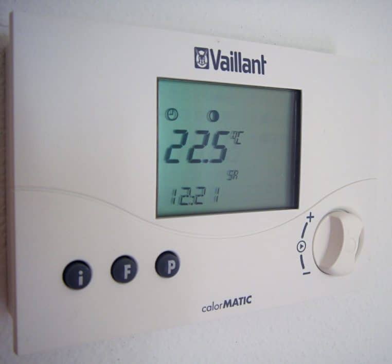 Thermostat numérique placé dans un séjour ; indispensable pour la régulation pièce par pièce et les économies.