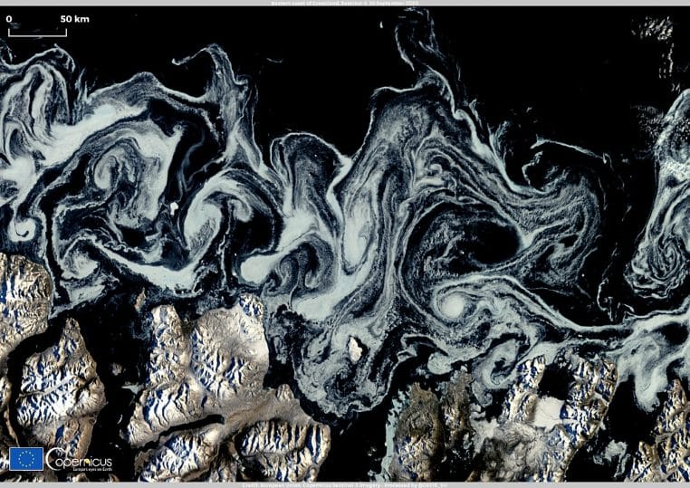 Vue couleur réelle de la glace de mer le long de la côte est du Groenland, montrant des tourbillons et chenaux d’eau libre.