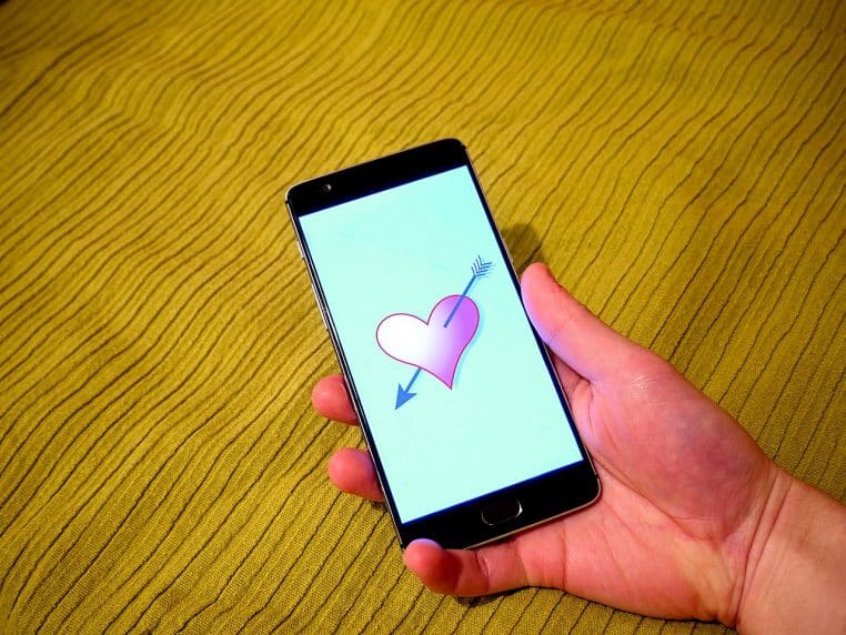 Illustration horizontale d’un écran de smartphone montrant une interface stylisée d’application de dating avec cœur.