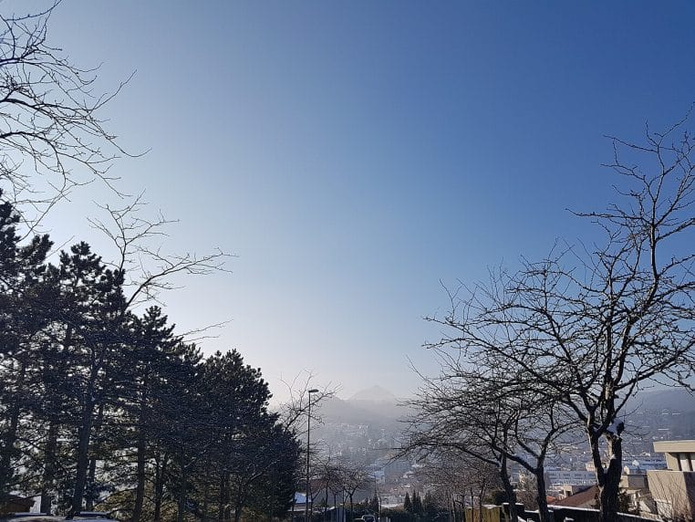 Paysage enneigé du parc de Montjuzet à Clermont-Ferrand, allées blanches, arbres givrés et horizon urbain adouci.