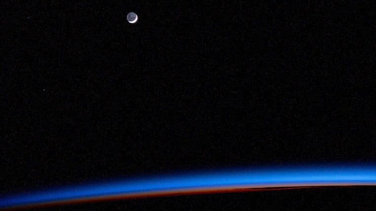 Fin croissant de Lune au-dessus de l’horizon terrestre, lueur bleutée de l’atmosphère, image capturée depuis l’ISS.