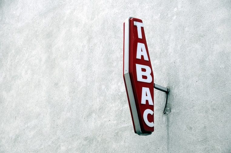 Enseigne rouge de débit de tabac à Paris fixée en façade, vue horizontale permettant d’identifier un commerce typique de quartier