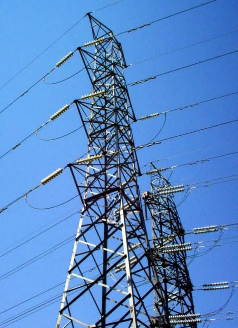 Deux pylônes de haute tension reliés par des conducteurs, structures métalliques en treillis sur ciel dégagé, vue latérale.