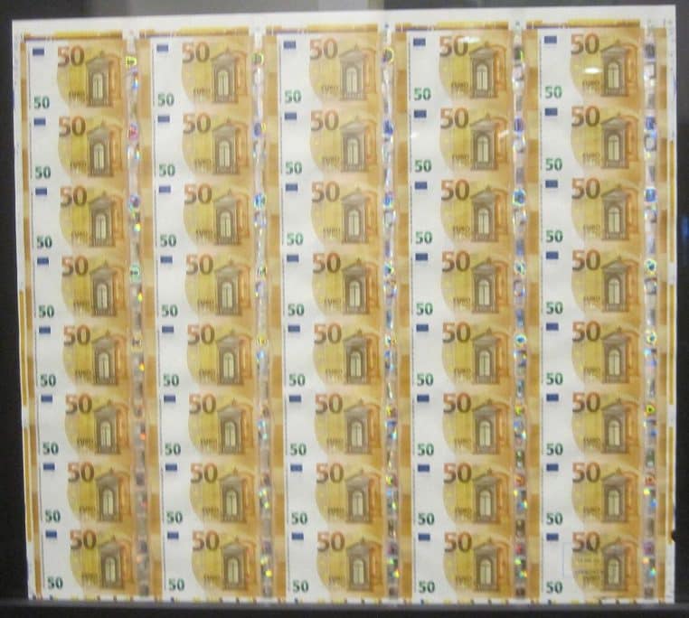 Bande non coupée de billets de 50 € exposée à la Monnaie de Paris, vue rapprochée en plan horizontal montrant détails de sécurité.