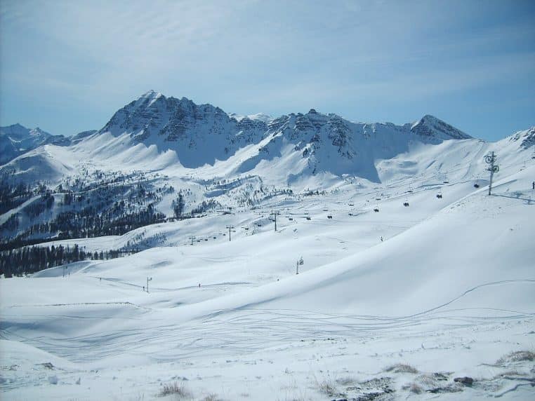 Vue panoramique des pentes enneigées de Vars avec télésièges et crêtes montagneuses sous un ciel bleu d’hiver limpide.
