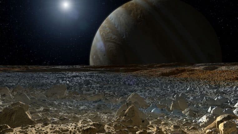 Vue conceptuelle depuis la surface glacée d’Europe, avec un terrain chaotique au premier plan et Jupiter dominant l’horizon.