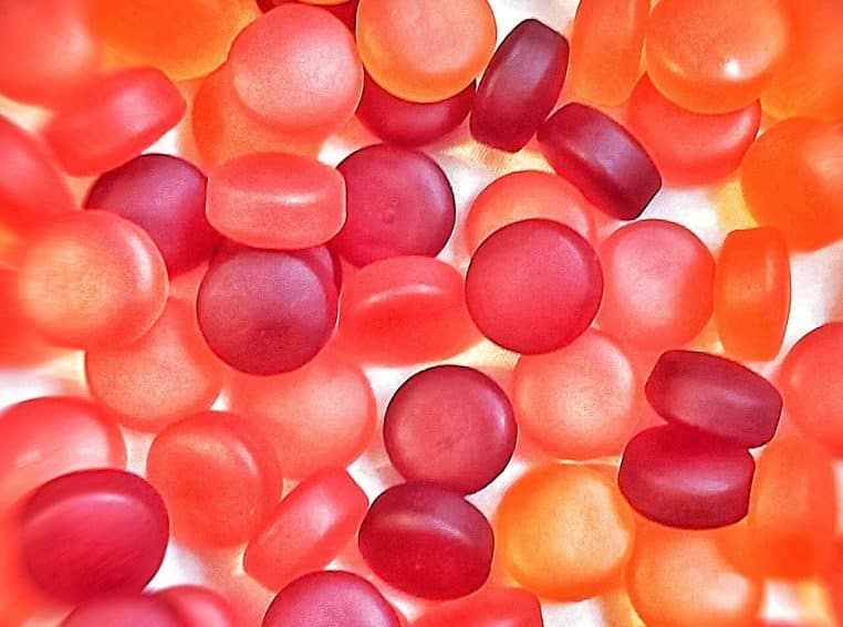 Gros plan coloré sur des gummies de vitamine D rouges et orangés, rappelant les compléments attractifs vendus au grand public