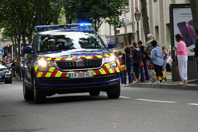 Voiture de la gendarmerie française en stationnement, vue latérale sur une voie urbaine en plein jour.