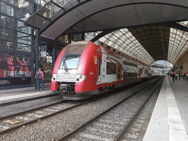 Rame TER 2N NG aux couleurs monégasques stationnée à Nice-Ville, plan large montrant quais, caténaires et façade.