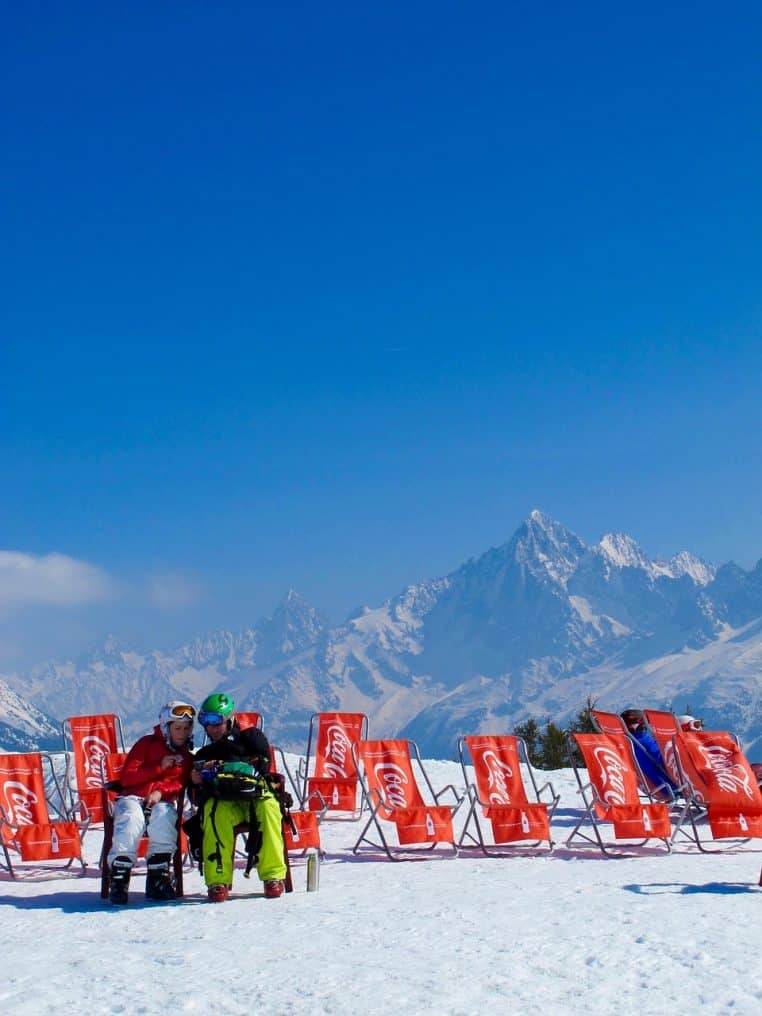 Panorama de station de ski dans les Alpes avec télésièges au repos, pentes enneigées et ciel d’hiver légèrement voilé.